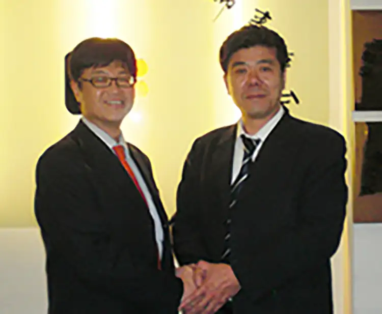 大連の提携会計事務所の所長・高先生（右）と提携の握手をする当社代表・黒田（左）